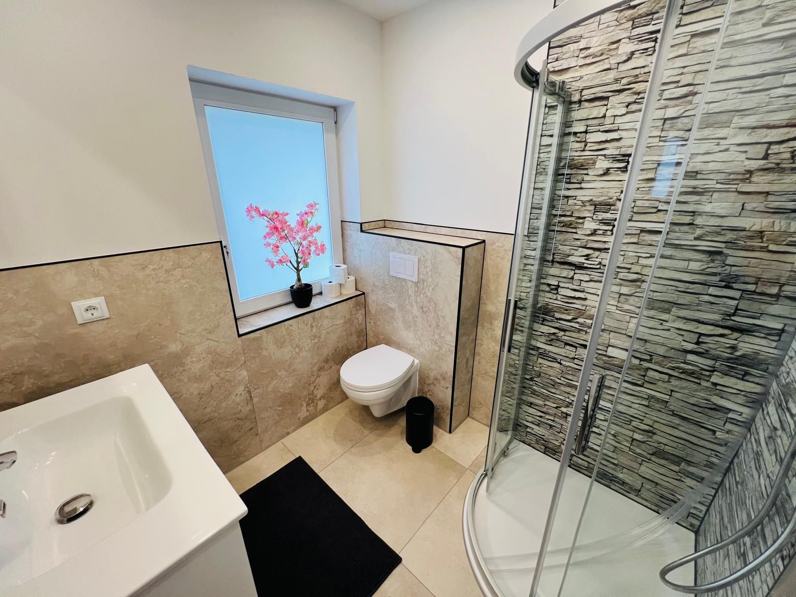 Modernes, sauberes Badezimmer mit großer Dusche, gutem Licht und ansprechender Ausstattung — sehr funktional und pflegeleicht für einen Monteur.